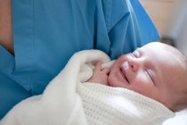 Enfermeira feminina segurando bebê recém-nascido envolto . — Fotografia de Stock
