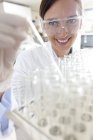 Женщина-ученый берет пробирку из подноса для научных исследований . — стоковое фото