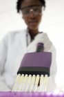 Primer plano de pipeteo científico femenino con pipeta multicanal . - foto de stock