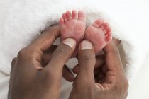 Manos masculinas sosteniendo pies recién nacidos . - foto de stock