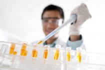 Close-up of male scientist pipetting into test tubes. — Stock Photo