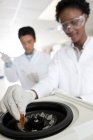 Close-up de centrífuga com amostra em tubo nas mãos dos cientistas . — Fotografia de Stock