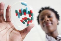 Female scientist holding petri dish with pills. — Stock Photo