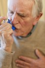 Retrato de homem idoso usando inalador de asma . — Fotografia de Stock