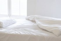 Unmade empty bed in sunlight. — Stock Photo
