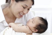 Mother smiling and holding sleeping baby girl. — Stock Photo
