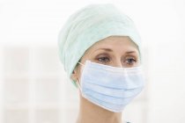 Female surgeon wearing surgical mask and cap. — Stock Photo
