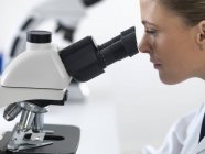 Científica femenina usando microscopio . - foto de stock
