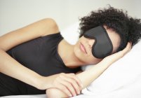 Afrikanische Amerikanerin schläft in schwarzer Schlafmaske. — Stockfoto