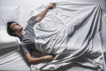 Overhead view of young man sleeping in bed. — Stock Photo