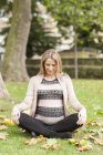 Pregnant woman meditating in park. — Stock Photo