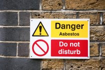 Asbest-Warnschild an Ziegelmauer. — Stockfoto