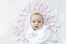Bébé garçon enveloppé dans une couverture avec des cœurs autour de la tête . — Photo de stock