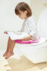 Jeune fille lecture sur la toilette — Photo de stock