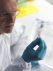 Un médecin légiste détient un échantillon d'ADN contenant du phial . — Photo de stock