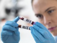 Cientista feminina que detém amostras de sangue em tubos de ensaio . — Fotografia de Stock