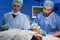 Cirujano asiático ajustando anestésico a paciente femenino - foto de stock