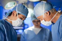 Surgical team in face masks working in operating theatre. — Stock Photo