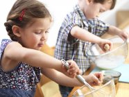 Близнецы-дошкольники пекут на домашней кухне . — стоковое фото