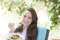 Young woman eating vegetable salad with fork. — Stock Photo