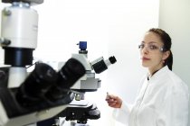Mujer joven en gafas usando microscopio
. - foto de stock