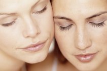 Close-up portrait of two young women with eyes closed. — Stock Photo