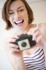 Woman holding camera and looking in camera. — Stock Photo