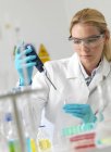 Female researcher pipetting liquid in science laboratory. — Stock Photo