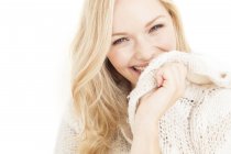 Молода жінка посміхається і закриває обличчя светром . — стокове фото