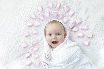 Baby boy wrapped in blanket with hearts around head. — Stock Photo