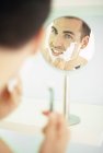 Взрослый мужчина бреется перед зеркалом . — стоковое фото