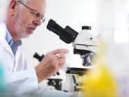 Mature scientist using microscope for biological research. — Stock Photo