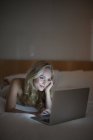 Junge Frau benutzt Laptop im Bett. — Stockfoto