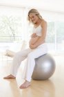 Mulher grávida sentada em uma bola de exercício . — Fotografia de Stock