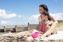 Madre e figlia seduti sulla spiaggia e guardando la vista
. — Foto stock