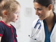 Pediatra hablando con niña en edad preescolar . - foto de stock