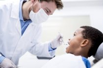 Médico examinando dentes de menino na clínica dentária . — Fotografia de Stock