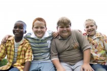 Group of boys sitting side by side outdoors. — Stock Photo