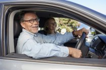 Seniorenpaar sitzt im Auto und lächelt. — Stockfoto