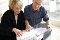 Mature couple signing forms indoors. — Stock Photo