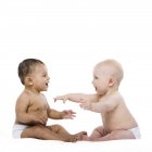 Baby girl and baby boy sitting and playing on white background. — Stock Photo