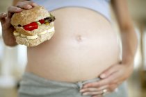 Vista recortada de la mujer embarazada con hamburguesa saludable . - foto de stock