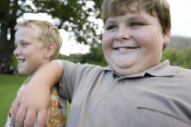 Edad elemental niño obeso apoyado en el hombro amigo . - foto de stock