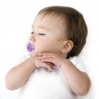 Sleeping baby girl with purple pacifier. — Stock Photo