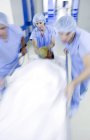 Emergency team pushing hospital gurney with patient in corridor. — Stock Photo