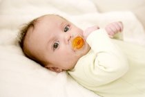 Bebê menina chupando manequim na cama . — Fotografia de Stock