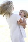 Grandmother in white clothing embracing granddaughter on white. — Stock Photo