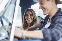 Young couple sitting in car and laughing. — Stock Photo