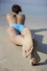 Femme en maillot de bain bleu bronzant sur la plage . — Photo de stock