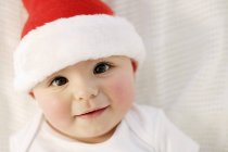 Niño en Santa sombrero sonriendo y mirando en la cámara . - foto de stock